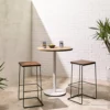 Two Paperclip Barstools and a table on a brick wall.