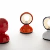 Three different colored Eclisse Table Lamps on a white surface.