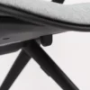 A close up of a black chair with a grey fabric seat.
