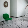 A green Tacchini Kelly Easy chair sits on a black and white tiled floor.