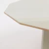 Edge of a minimalist wooden table against a white background.