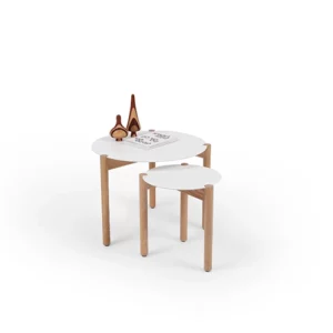 A small round stool placed next to a wooden table with a book and a pair of scissors on top, against a white background.