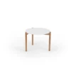 Simple round white tabletop with wooden legs on a plain background.