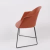 Modern terracotta-colored chair with a sleek design and metal base against a white background.