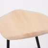 A modern wooden seat with a textured surface on black metal legs against a white background.