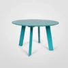 Round turquoise table with four legs against a white background.