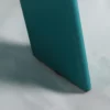 A close-up of a teal object with a pointed edge resting on a white surface.