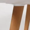 Close-up of a wooden table leg meeting a white tabletop.