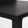 Close-up of a black wooden table corner, highlighting the wood grain and smooth finish.