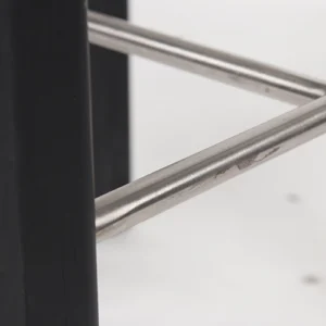 Close-up of a metal bar connected to a black structure with a white background.