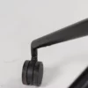 Close-up of a black chair leg with dual wheel casters on a white surface.