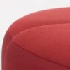 Close-up of a red fabric upholstered object with a smooth, curved surface.