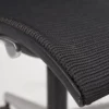 Close-up of a black mesh office chair with a focus on the texture and armrest adjustment button.