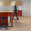 Modern kitchen area featuring the Met Counter Stool by Stylecraft. The bar stool has a sleek design with a blue lacquered paint. The timber legs are crafted from American white ash, providing a sturdy and stylish foundation. The stool is positioned at a kitchen counter, with a minimalist and contemporary aesthetic. The space is well-lit with natural light, creating a bright and inviting atmosphere