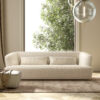 A brightly lit living space with large window with a Verzelloni Davos lounge in a light cream coloured fabric on a rug.