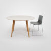 Gher from Arper is a modern round dining table with a white top and Oak wooden legs on a white background with a Catifa 46 Sled dining chair.