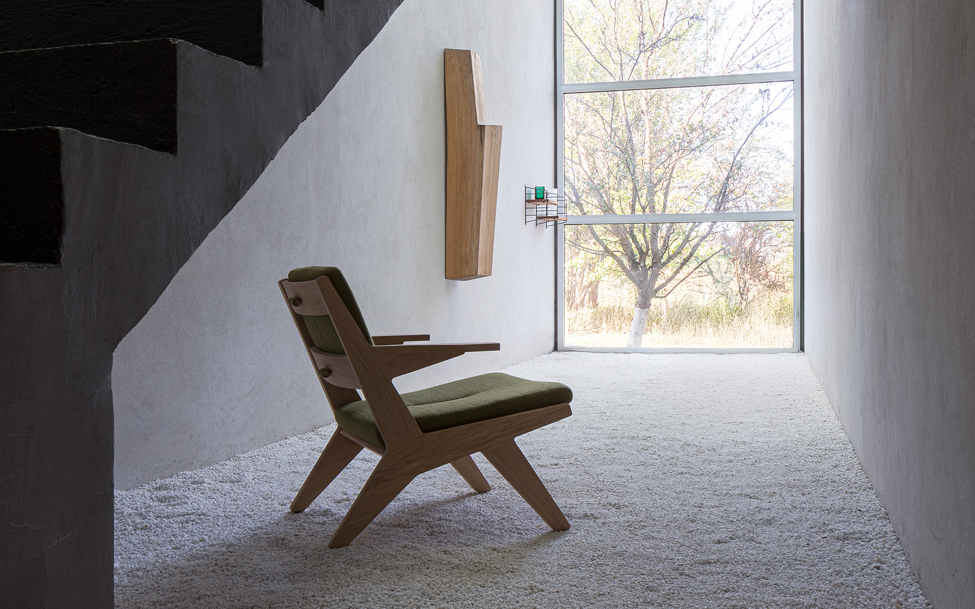A Toggle lounge armchair by Prostoria, featuring wooden arm and legs in Oak, within a small study nook.
